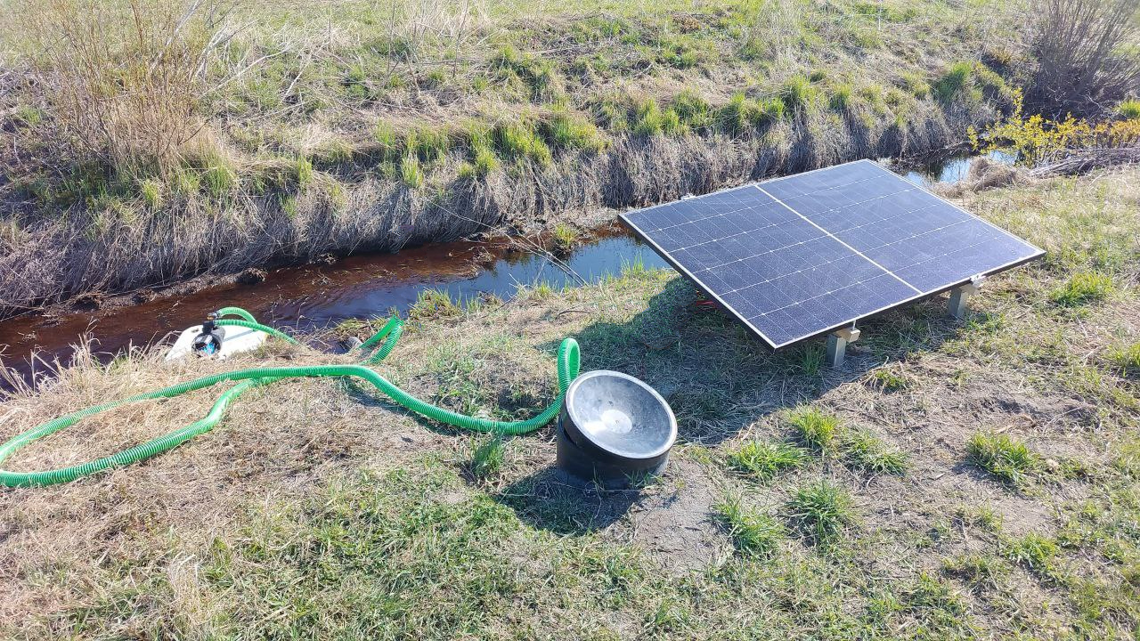 Salaojakasteupumppu vedessä. Rannalla aurinkopaneeli