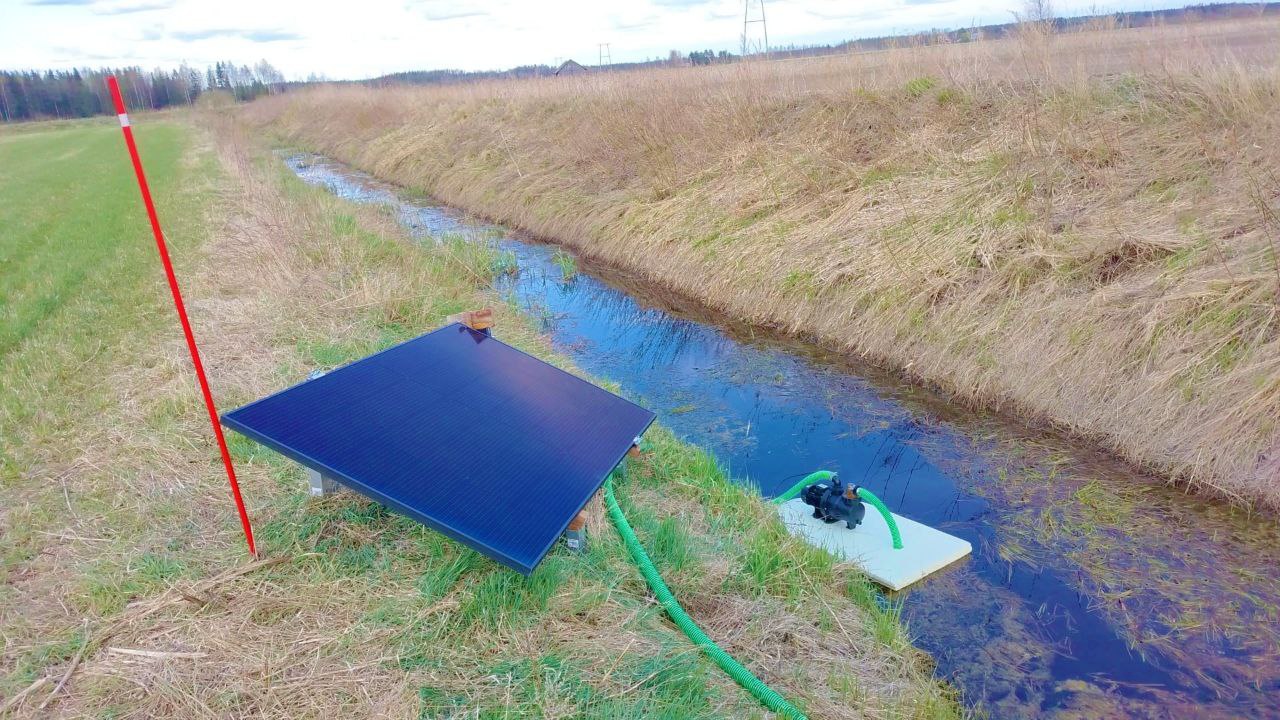 Salaojakasteupumppu vedessä. Rannalla aurinkopaneeli